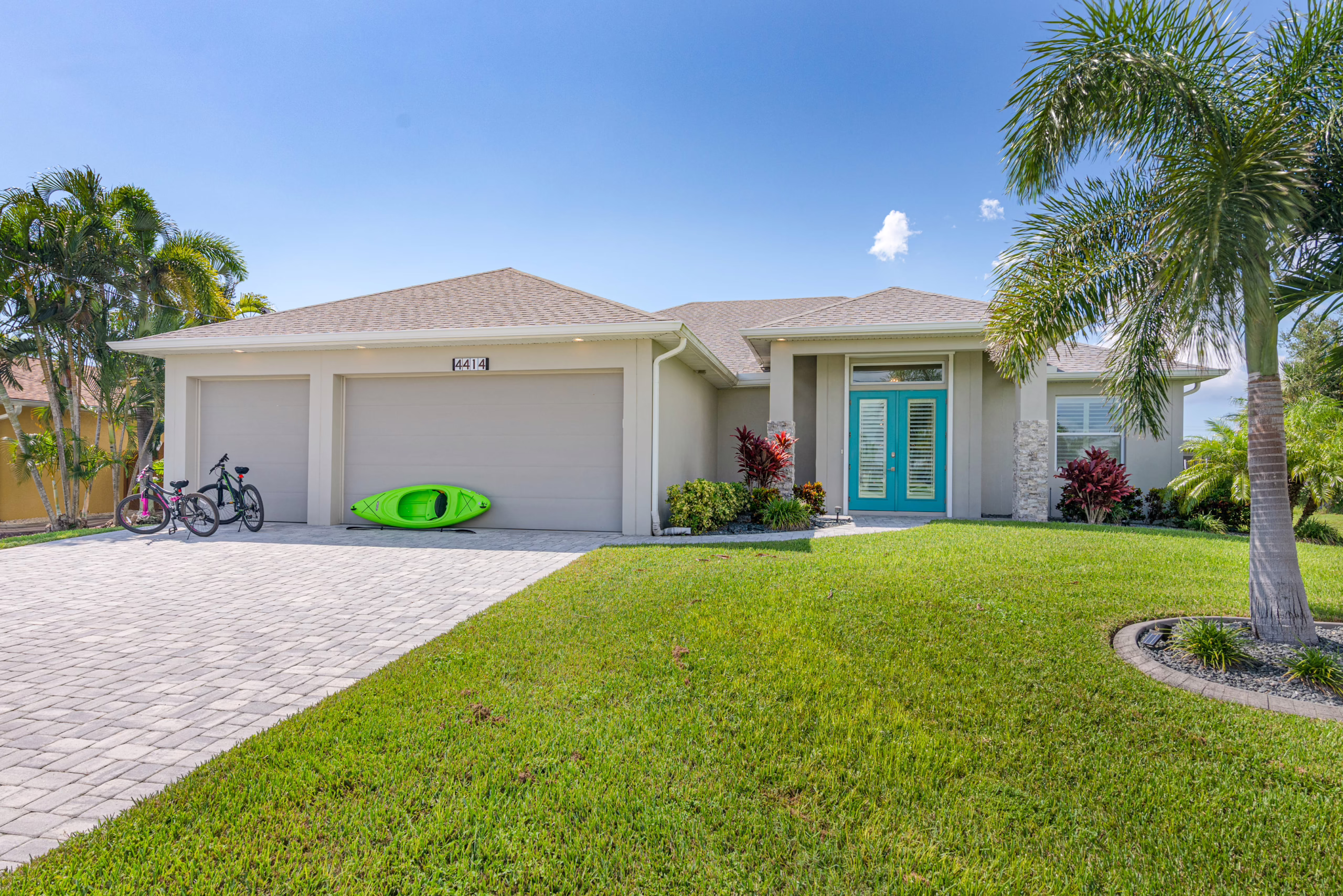 Front view of Villa Dandelion with driveway, garage, kayak, and palm tree landscaping in Cape Coral.